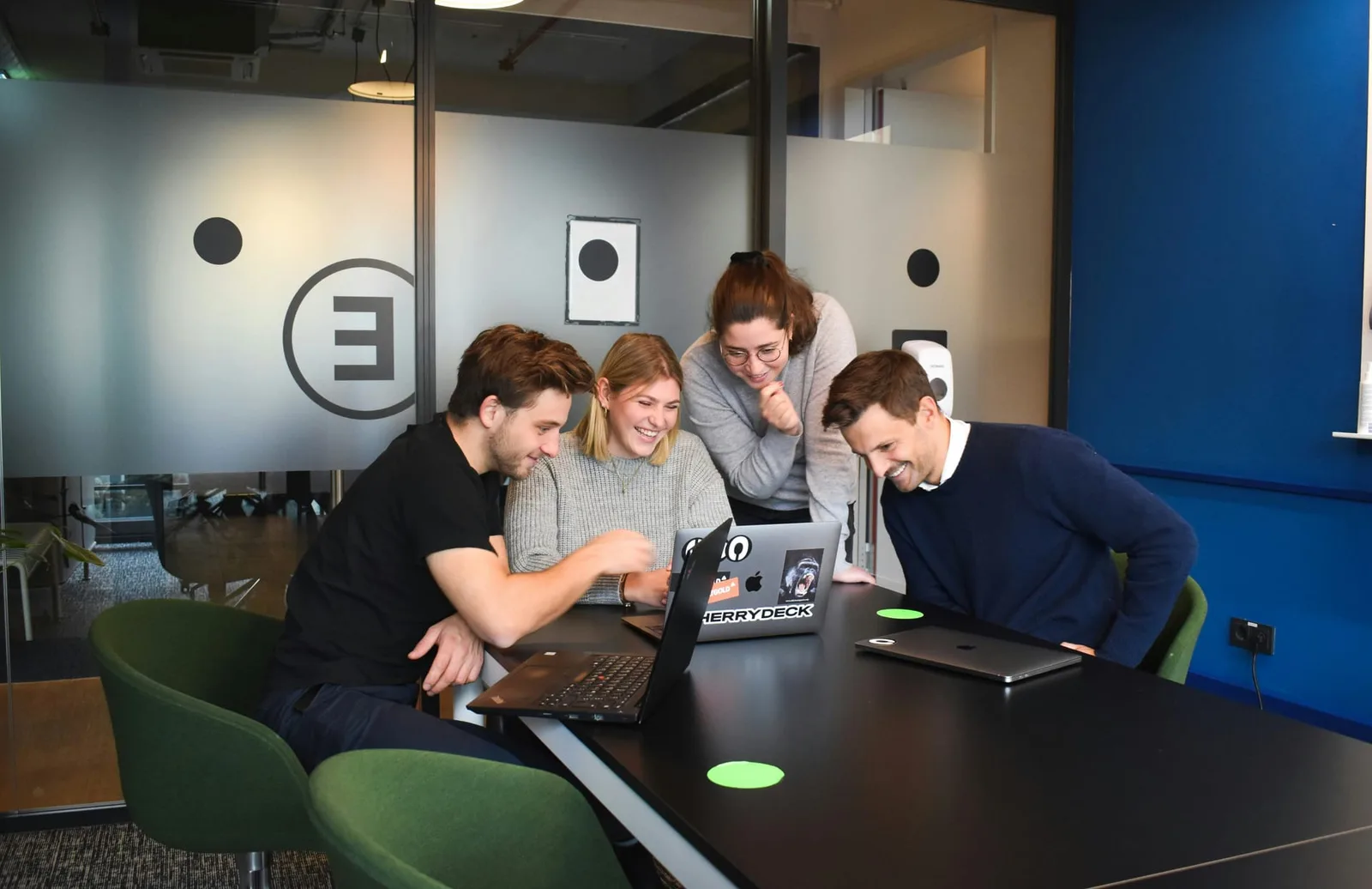 Quatre consultants souriants réunis autour d’un ordinateur portable dans un bureau moderne